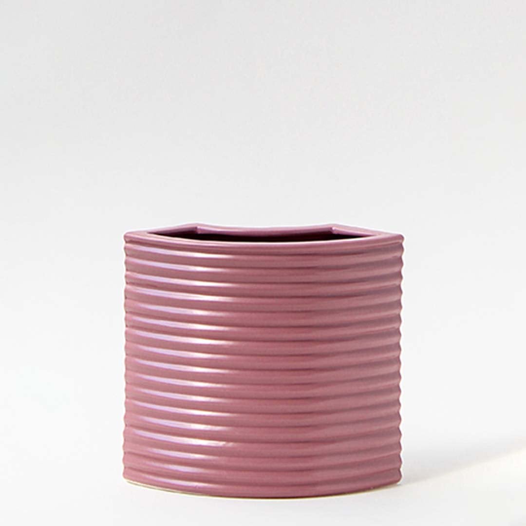 Mauve vase placed on a clean white background highlighting its ribbed curved design and modern angular shape that creates a stylish decorative accent for any space.