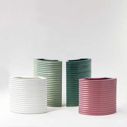 Set of green ceramic vases with ribbed texture arranged on a white background highlighting their geometric form and modern style.