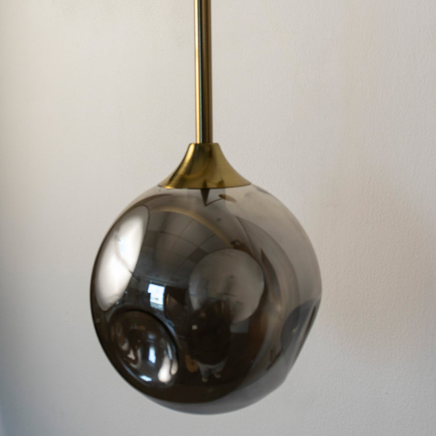 Closeup of smoked glass and gold metal pendant wall light for modern bedroom and luxury home decor spaces.