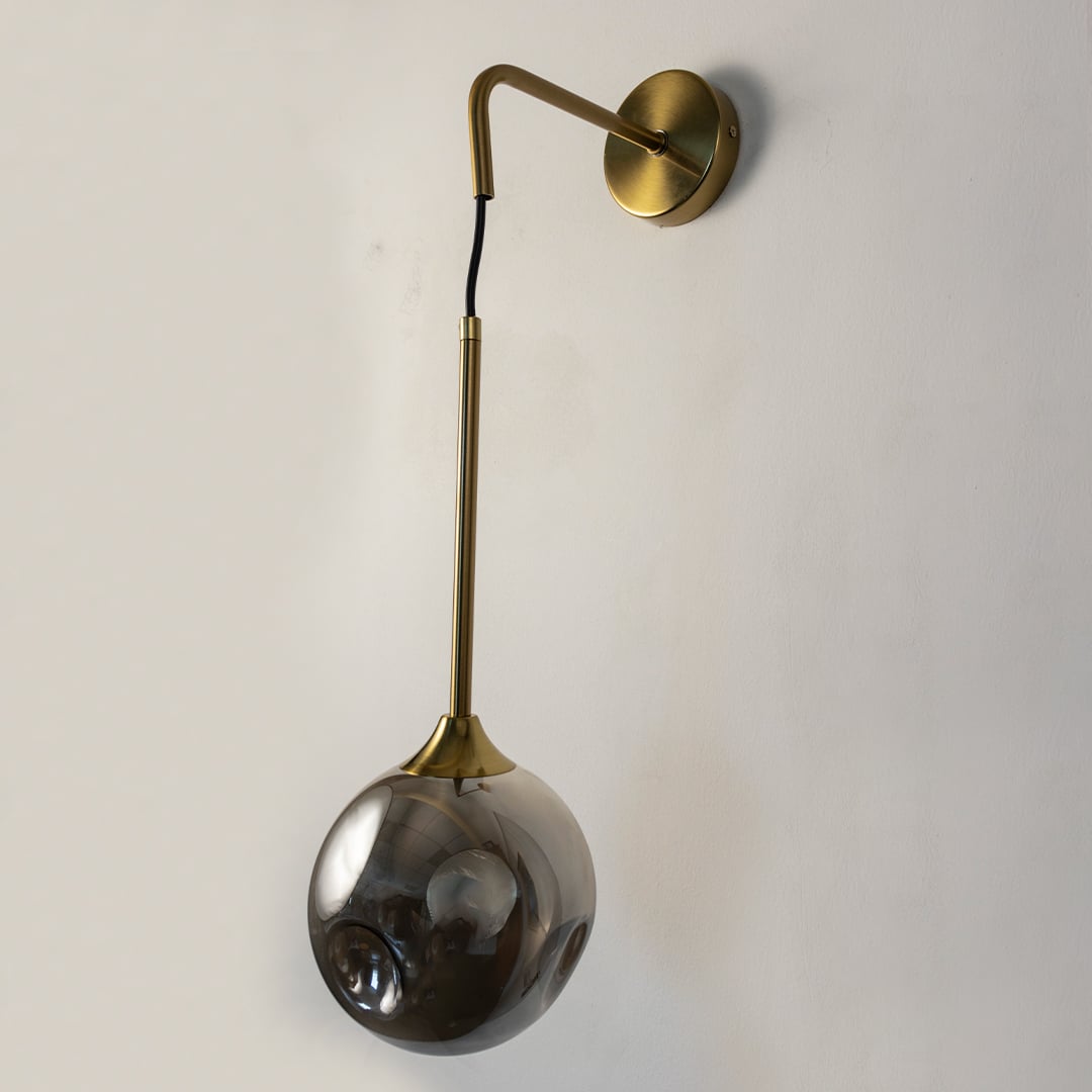 Elegant smoked glass and brass wall light on white background perfect for stylish contemporary living spaces.