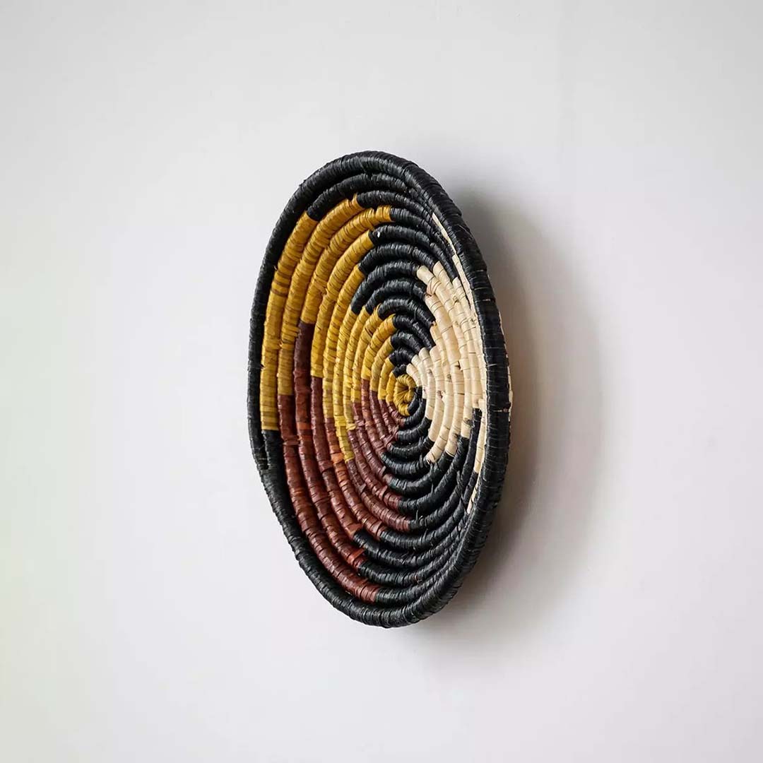Side view of decorative woven plate emphasizing its coiled structure thickness and smooth handcrafted finish.
