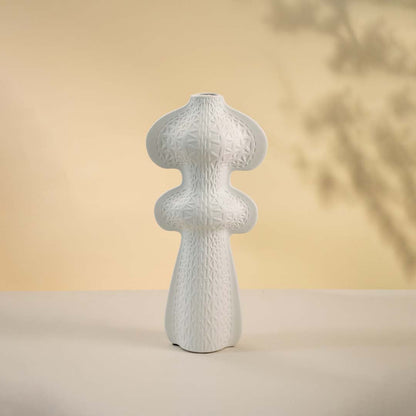 Matte white vase displayed on a white surface emphasizing its modern form and detailed geometric texture.