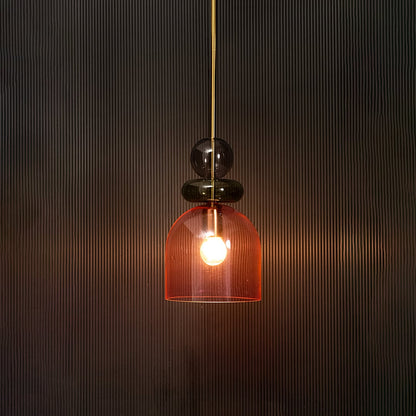 Unique pink glass pendant light illuminated beautifully against dark background highlighting soft glow.