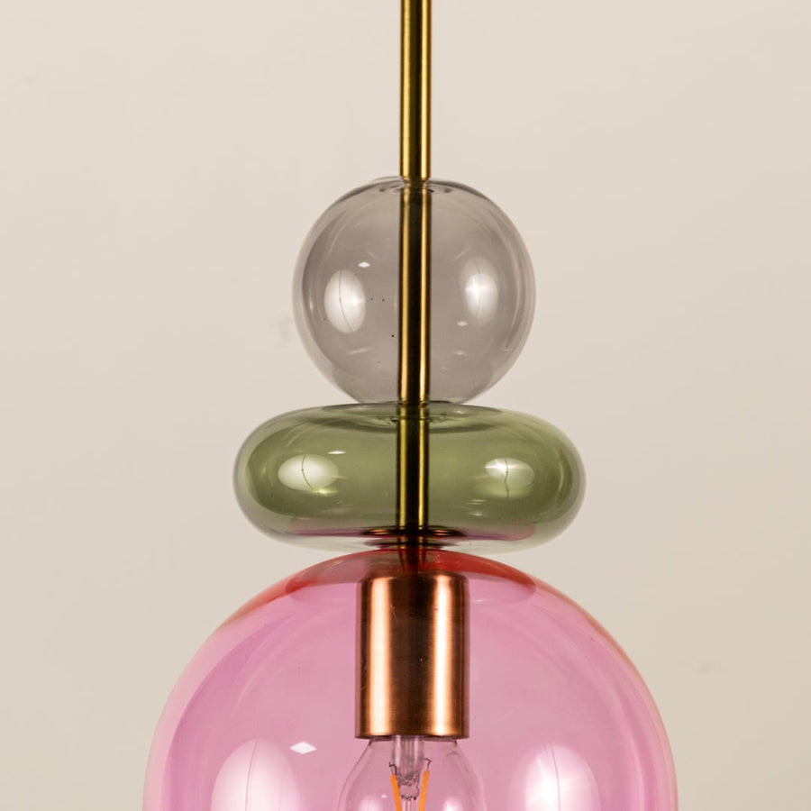 Close view of pink glass pendant light showing smooth texture colorful glass accents and elegant craftsmanship.