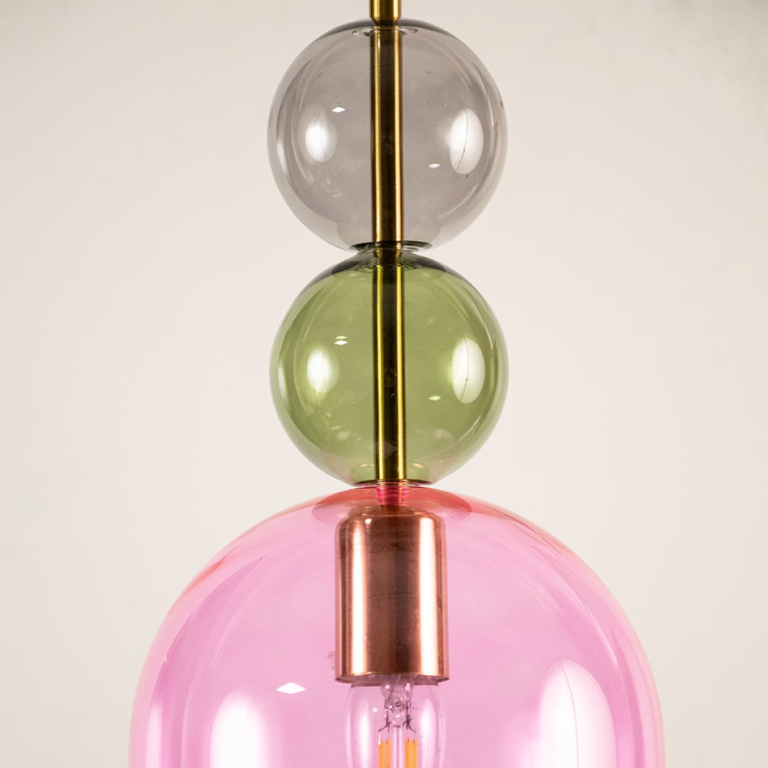 Close view of pink glass pendant light showing smooth glossy surface and colorful glass sphere detailing.
