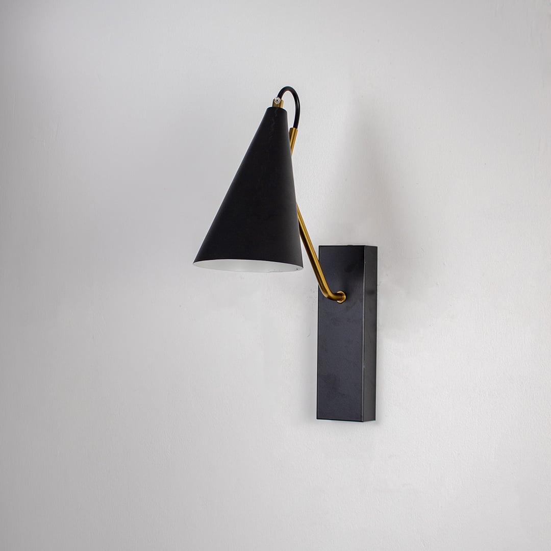 Contemporary black wall light with golden arm and sleek conical shade displayed off on black background for interiors.