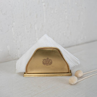 Brass tissue holder with crown engraving placed on a marble countertop styled in a cozy kitchen setting with soft light.