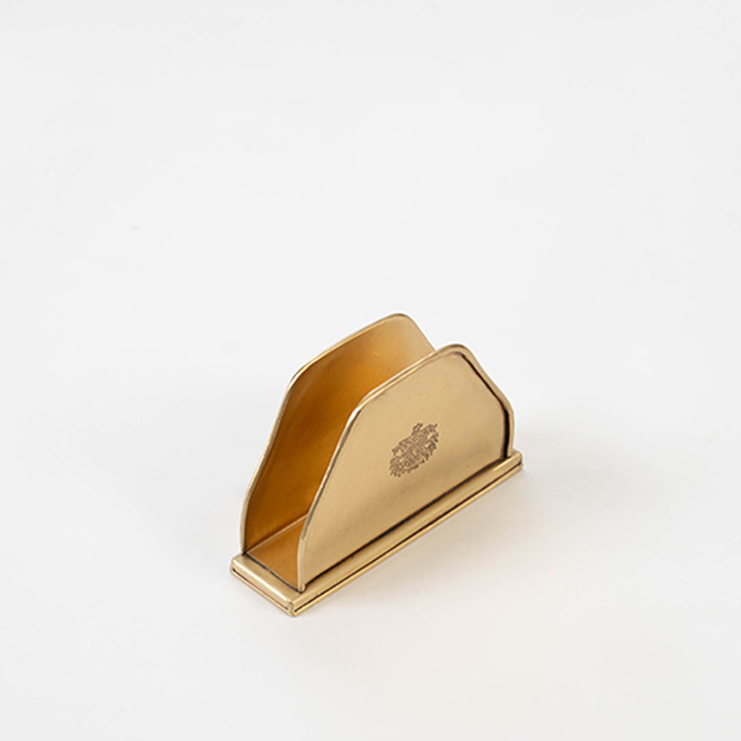 Contemporary metal napkin holder in gold finish for dining table or kitchen decor accessory placement white background.