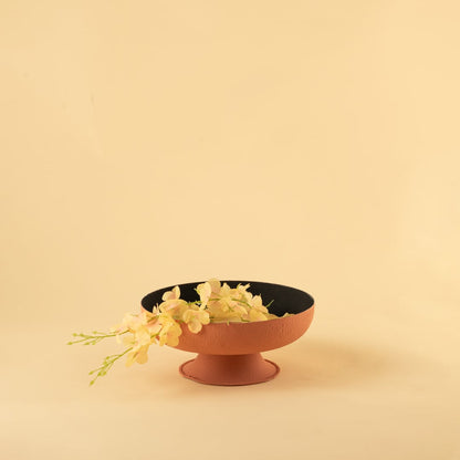 Terracotta textured metal pedestal bowl with black interior styled in a warm neutral scene adding earthy modern charm to decor.