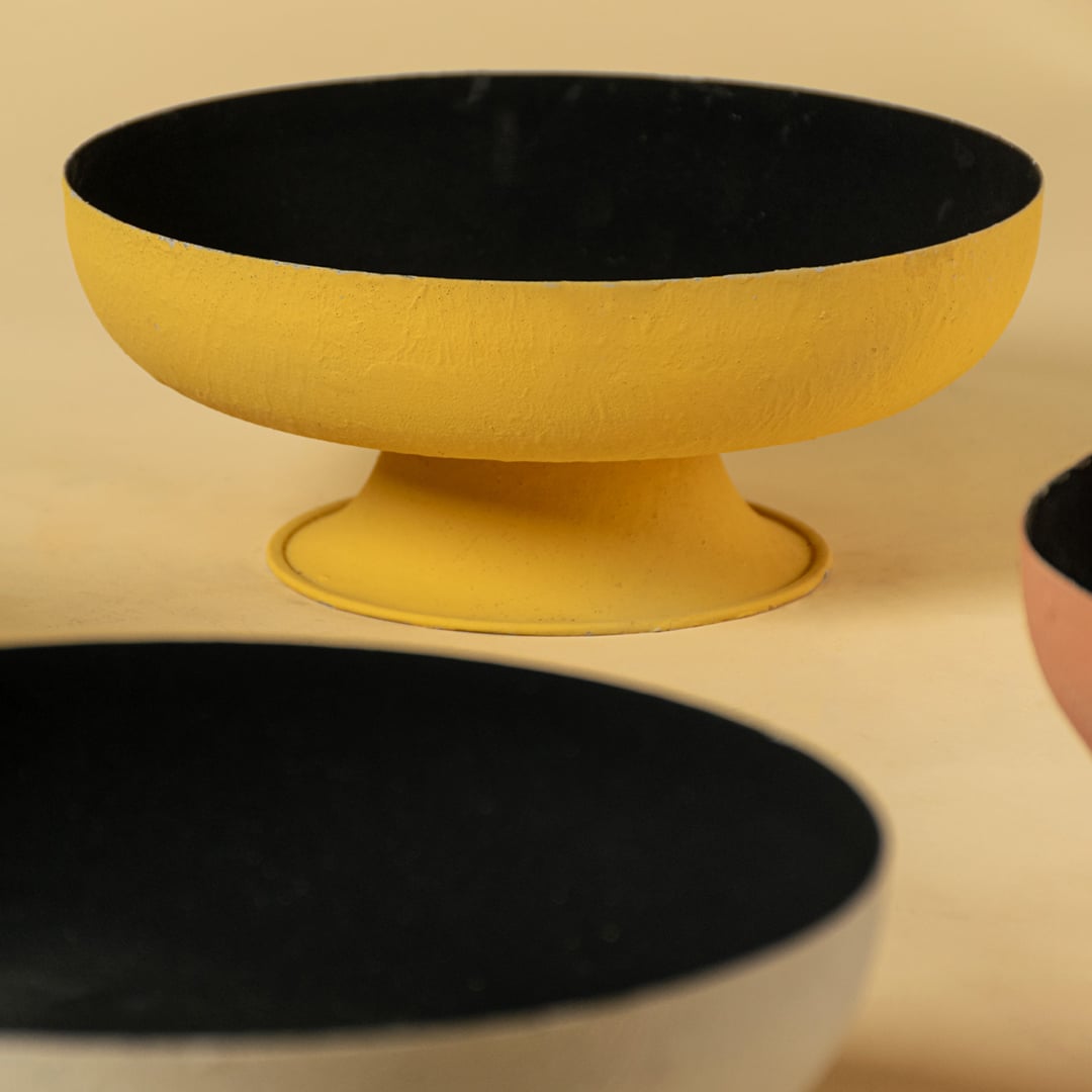 Closeup of terracotta metal pedestal bowl showing matte textured finish and deep black interior for a stylish decor accent.
