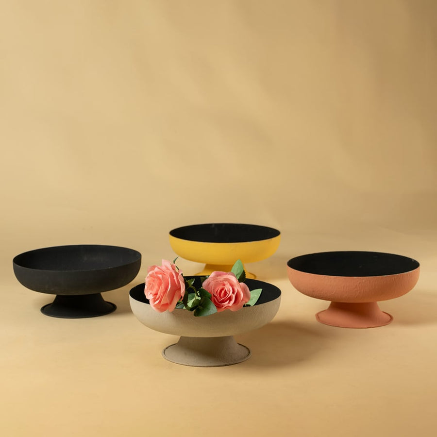 Yellow pedestal metal bowl grouped with decor pieces creating a vibrant contemporary look for living and dining spaces.