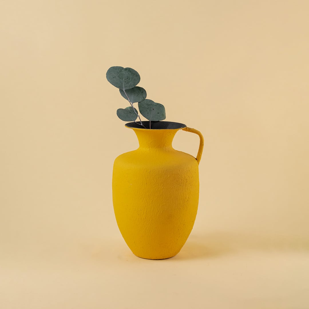 Yellow metal jug vase decor styled in a warm modern room adding a bright elegant accent to living room tables and corner spaces.