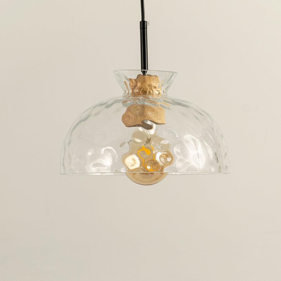 Clear wavy glass and brass metal pendant light designed for stylish dining room decor spaces.