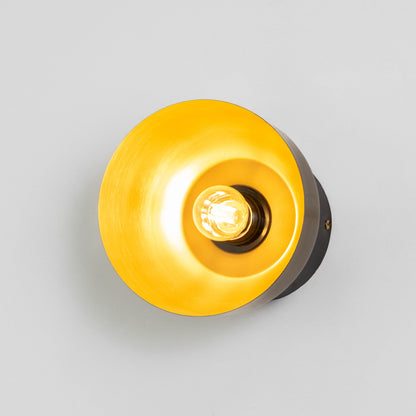 Contemporary wall light in gold metal finish with circular shade for bedroom or living decor lighting placement white background.
