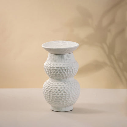 Artistic white ceramic vase placed on white background showcasing intricate handcrafted details and smooth sculptural design.