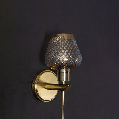 Detailed closeup view of the diamond textured amber glass shade and brass holder of the wall light fixture art.