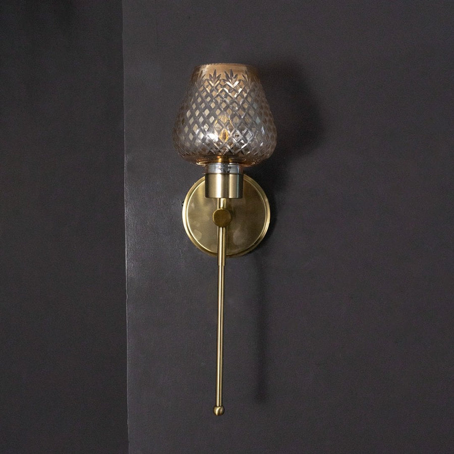 Sleek gold industrial wall sconce fixture turned off isolated on a pitch black background for dramatic contrast.