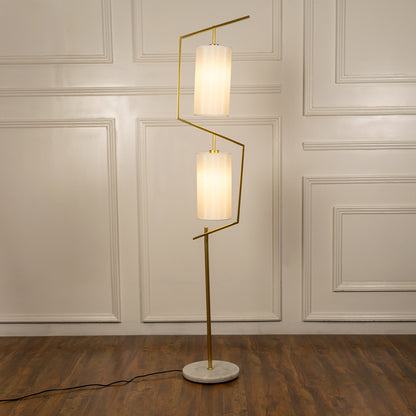 White floor lamp with geometric illuminated shades and brass stem creating elegant ambient lighting for modern spaces.