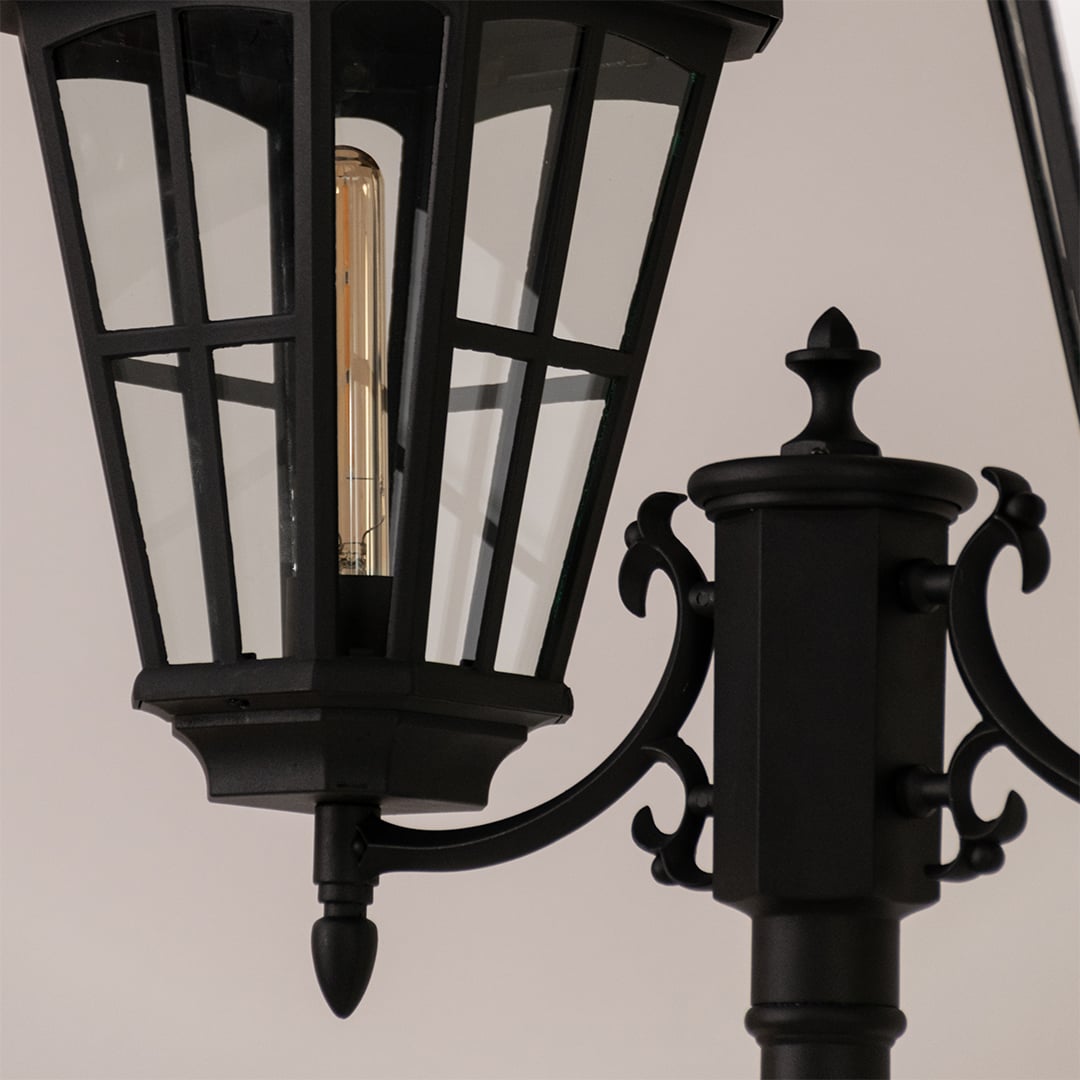 Detailed view of black outdoor lamp head highlighting glass panels and metal frame for vintage exterior decor.
