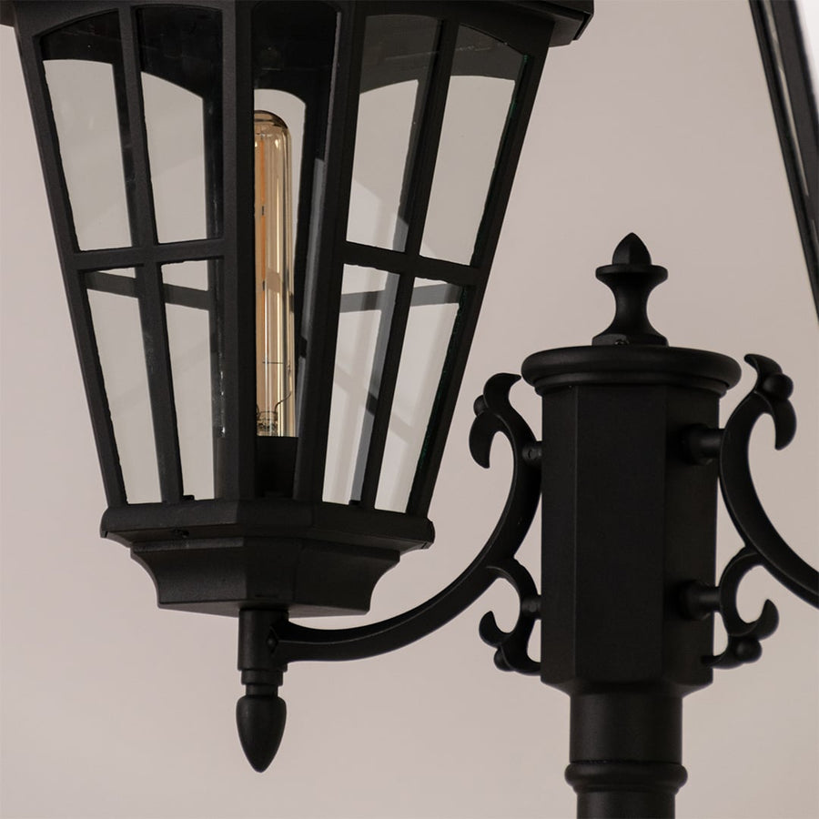 Detailed view of black outdoor lamp head highlighting glass panels and metal frame for vintage exterior decor.