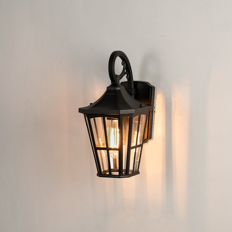 Black aluminum outdoor wall light on white background with a tapered windowpane clear glass shade for porch pathway decor.