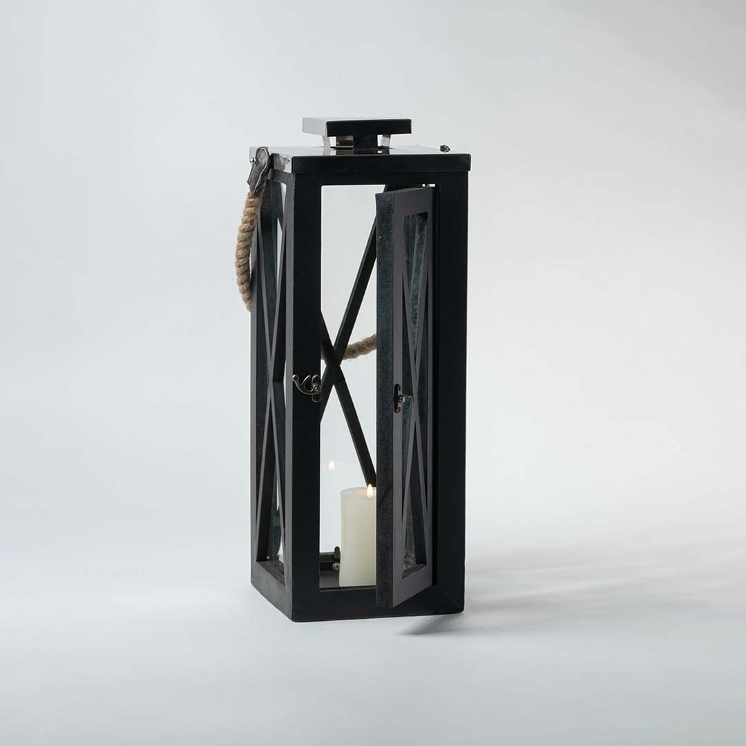 Black lantern illuminated on a white background showcasing the glow through its transparent glass windows.