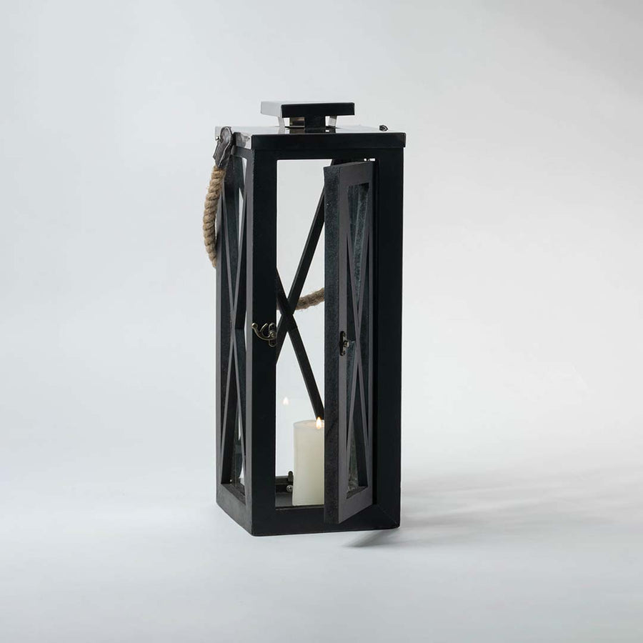 Black lantern illuminated on a white background showcasing the glow through its transparent glass windows.