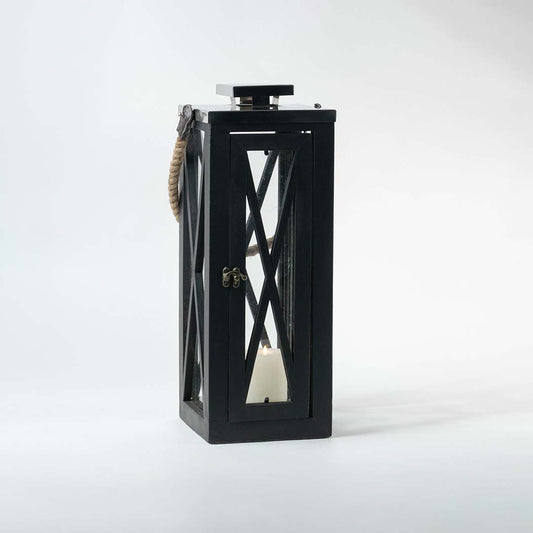Black lantern illuminated on a white background showcasing the glow through its transparent glass windows.