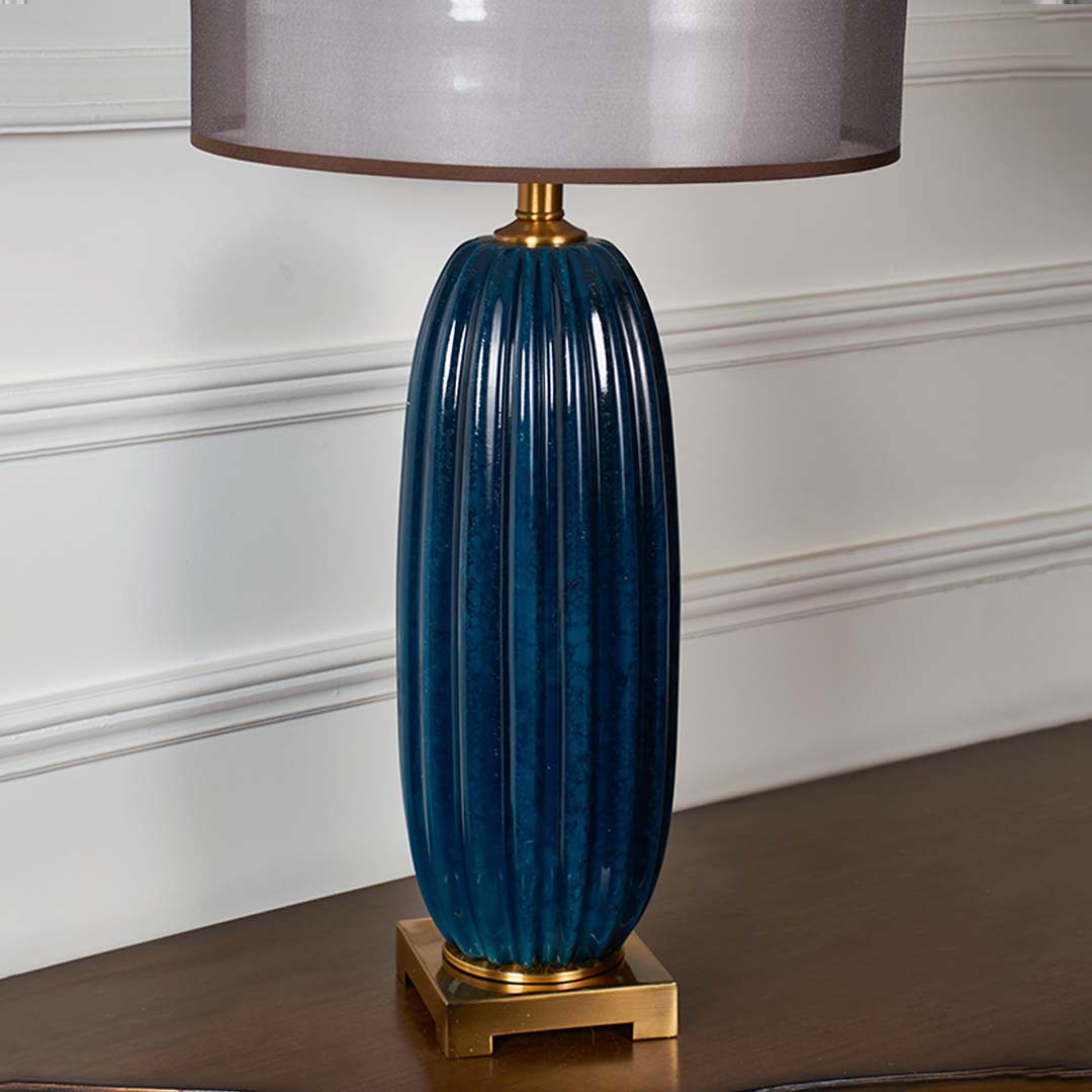 Blue ribbed glass table lamp with brass base designed for elegant modern decor and ambient lighting indoors.