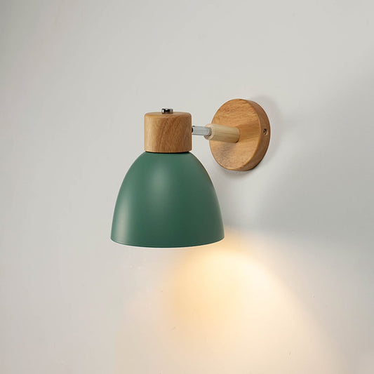 Green wall light with wooden mount glowing softly on a white wall bringing a natural and modern Scandinavian look.