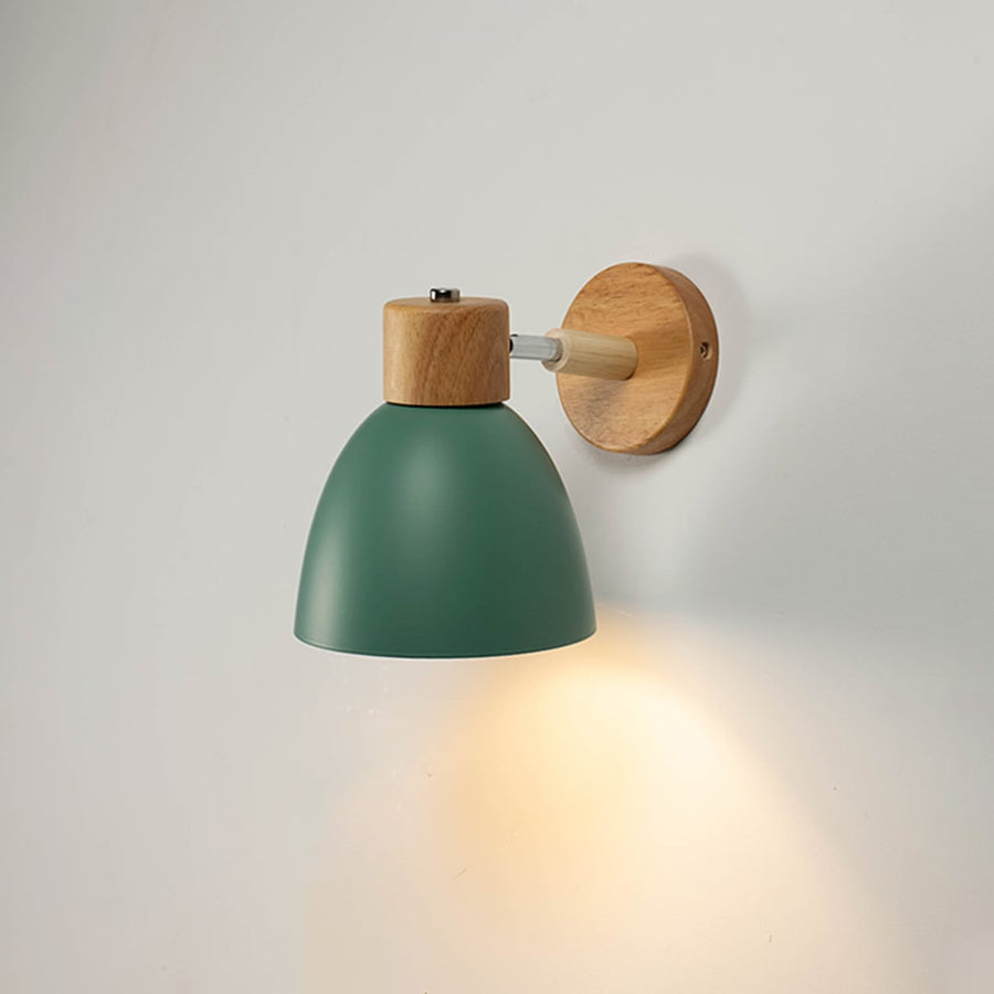 Green wall light with wooden mount glowing softly on a white wall bringing a natural and modern Scandinavian look.