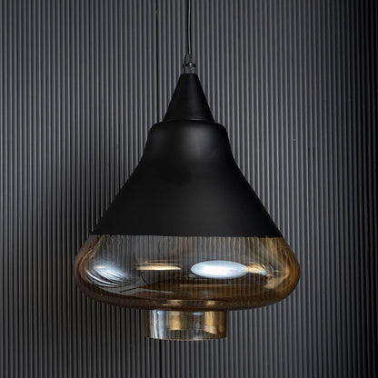 Amber glass pendant lamp turned off with smooth golden glass and black top shown against a black ribbed background.