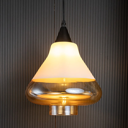Amber glass pendant lamp illuminated on a black ribbed background showing the rich golden hue and soft ambient glow.