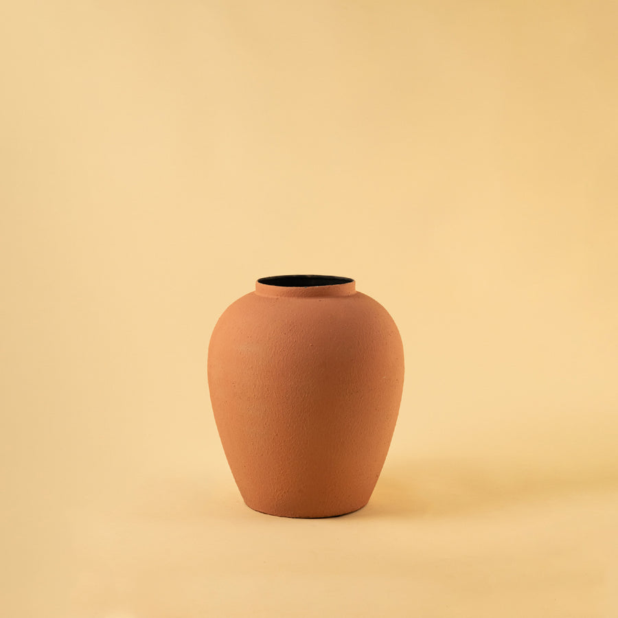 Sophisticated matte terracotta rounded metal vase for modern home decor and clean minimalist interior styling.