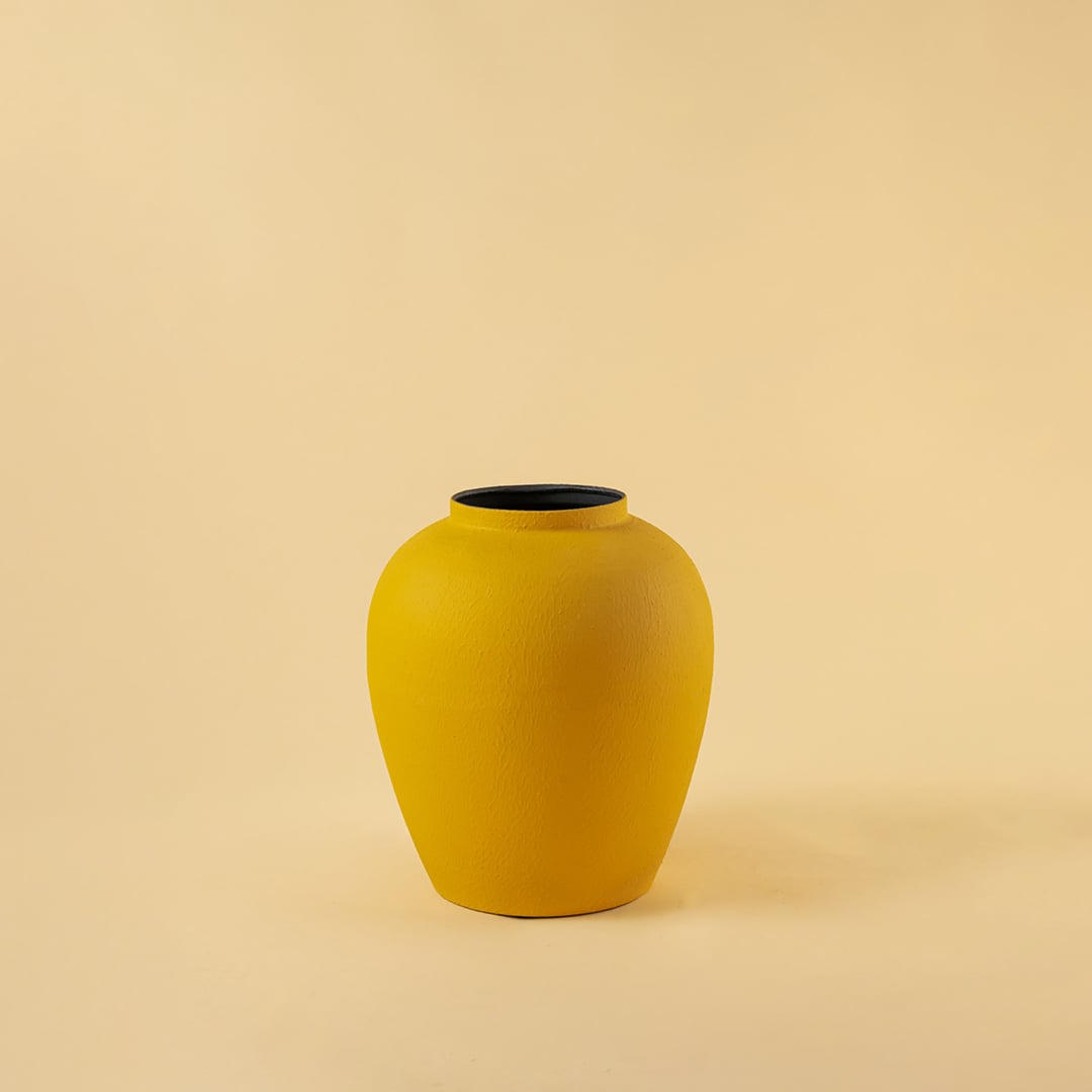 Yellow modern metal vase displayed on a clean white background highlighting its textured surface and sculpted form.