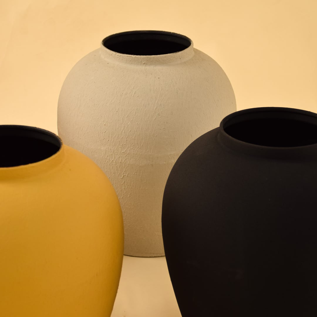 Closeup of yellow metal vase showing matte textured finish and rounded silhouette for a bold modern decor accent.