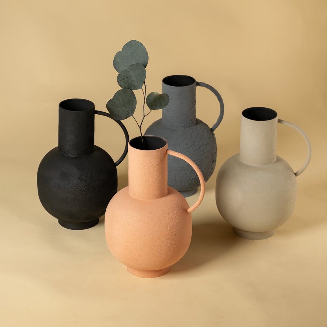 A group of decorative vases in peach grey black and beige tones arranged together to showcase their textured finishes rounded shapes and modern minimal design.