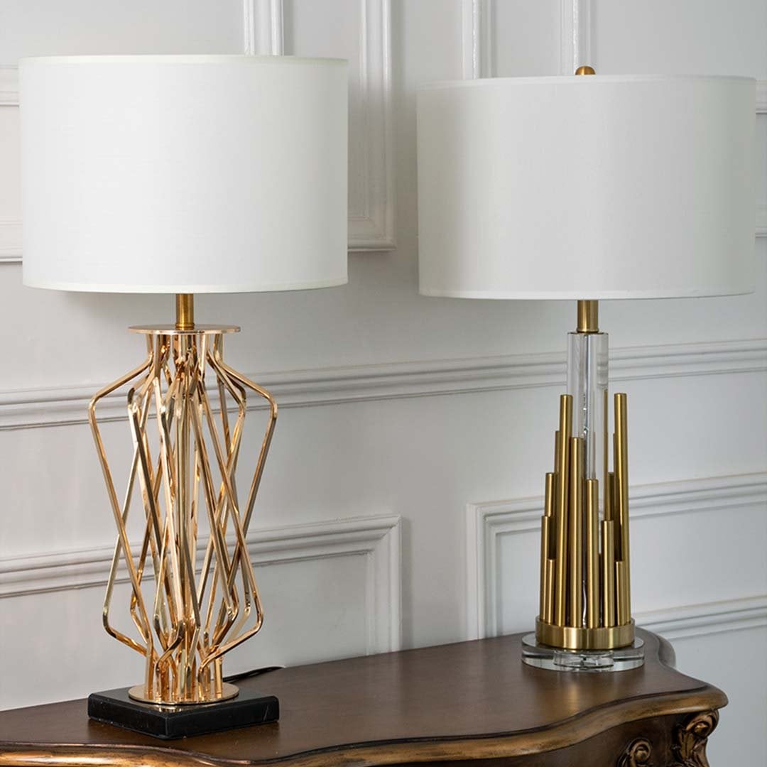Gold sculpted table lamps with white drum shades shown together with lights off highlighting artistic bases and refined modern design for upscale decor.