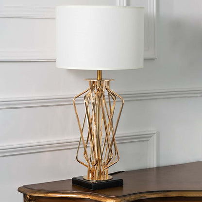 Gold sculpted table lamp with white drum shade and artistic twisted base displayed on a white background perfect for modern home styling and luxury interiors.