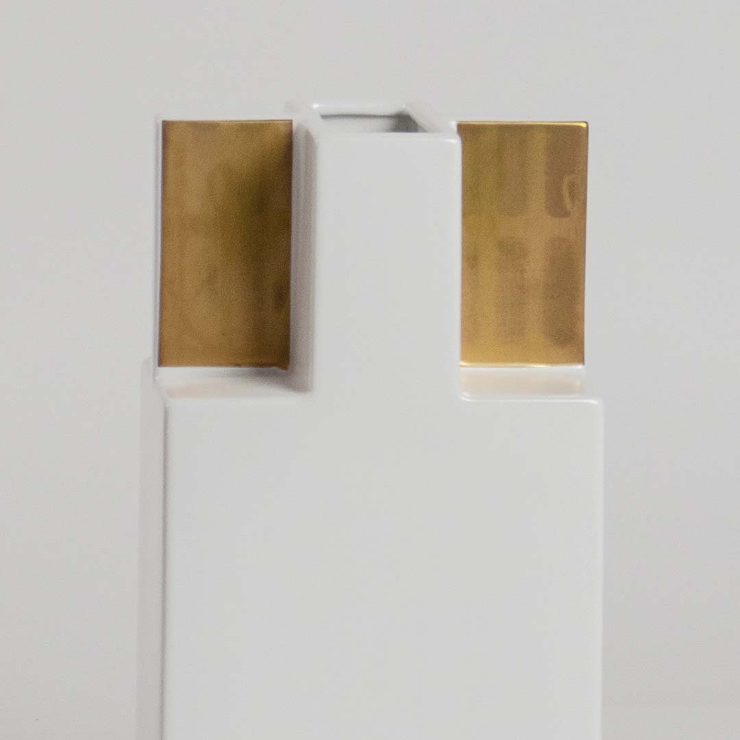 Closeup view of the white ceramic vase with gold top panels  showing its smooth finish  sharp structure  and elegant geometric form.