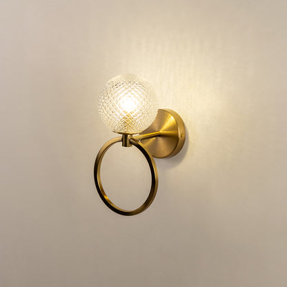 Gold finish wall light with textured glass shade emitting warm glow perfect for bedroom hallway wall decor on clean white background.