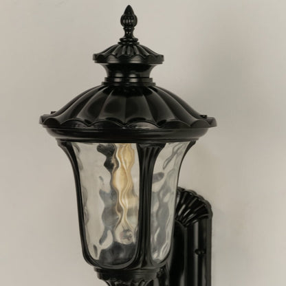 A closeup view of the outdoor wall lantern highlighting its sculpted antique finish textured glass panels and refined decorative detailing in a classic style.