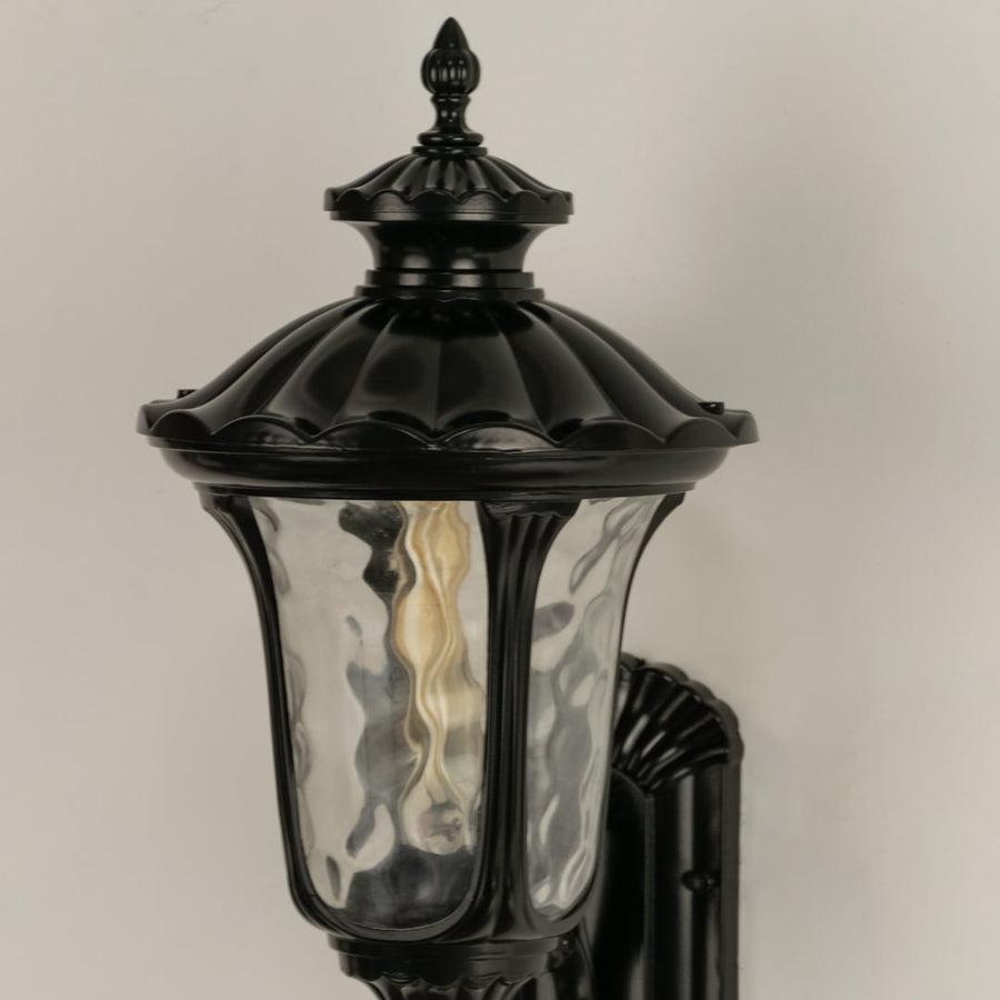 A closeup view of the outdoor wall lantern highlighting its sculpted antique finish textured glass panels and refined decorative detailing in a classic style.