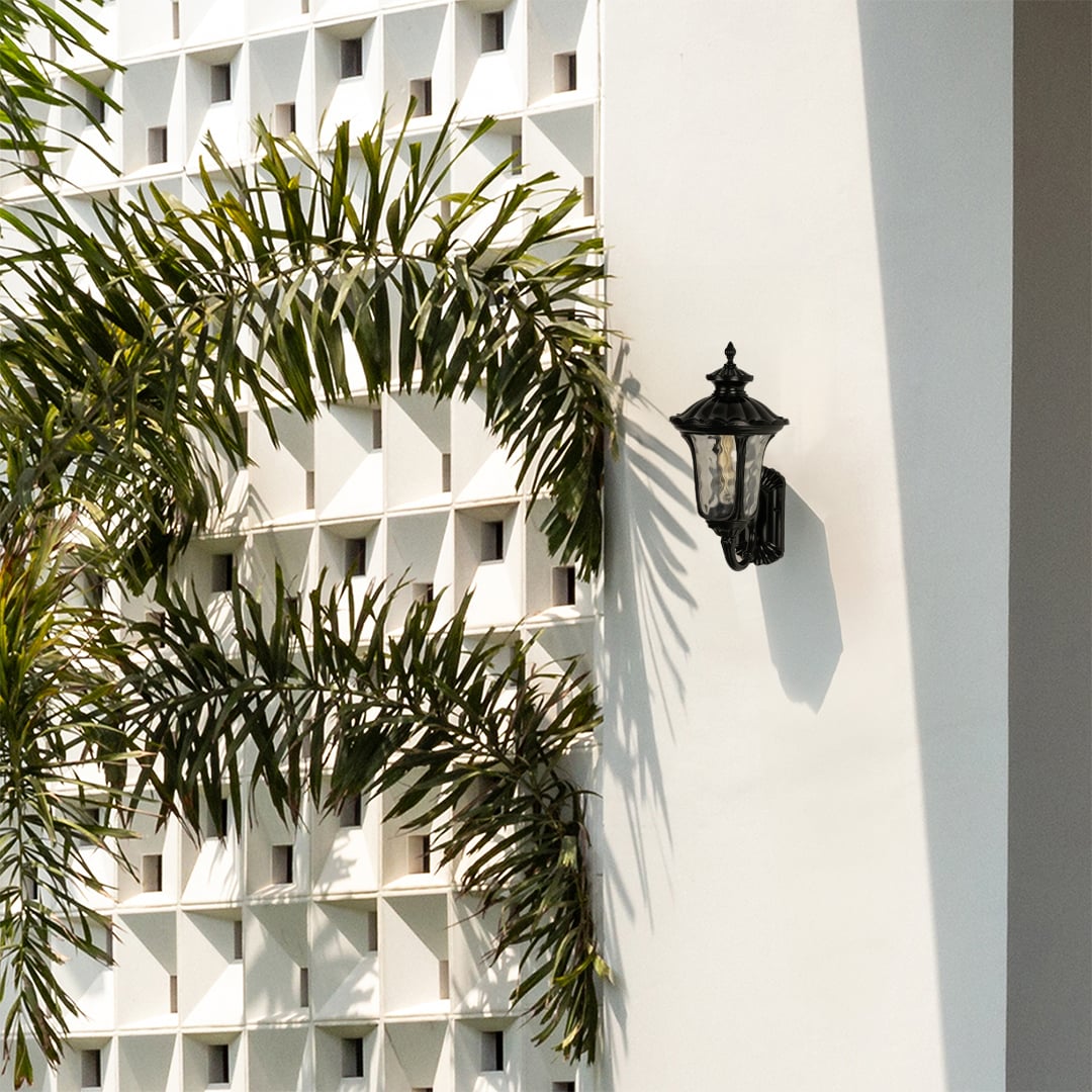 A classic outdoor wall lantern mounted beside an entryway wall creating a warm and welcoming glow with its elegant vintage design and illuminated light on.