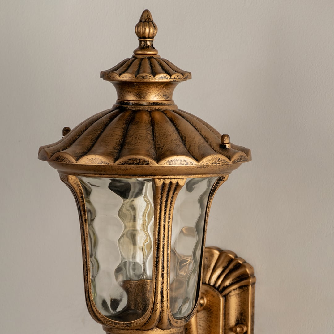 Closeup of gold metal outdoor wall lantern showing textured glass and ornate detailing for elegant outdoor wall lighting.