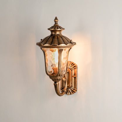 Antique brass outdoor wall lantern on white background with textured water glass shade for traditional porch decor.