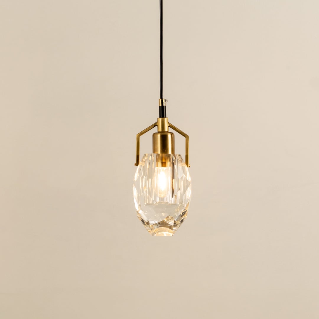 Crystal pendant light with polished metal accents glowing beautifully against a clean white background showcasing refined minimalist interior home decor lighting style.