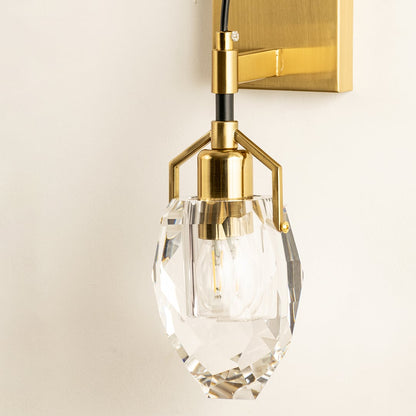 A gold and glass wall light with a sculpted shade glowing on a beige wall providing warm illumination and refined contemporary interior décor.