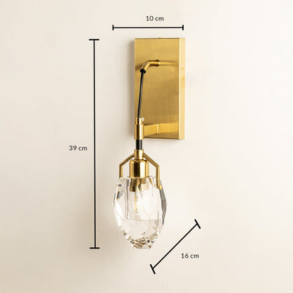 A gold and clear glass wall light mounted on a dark ribbed wall featuring a sculpted rounded shade offering refined classic décor styling.