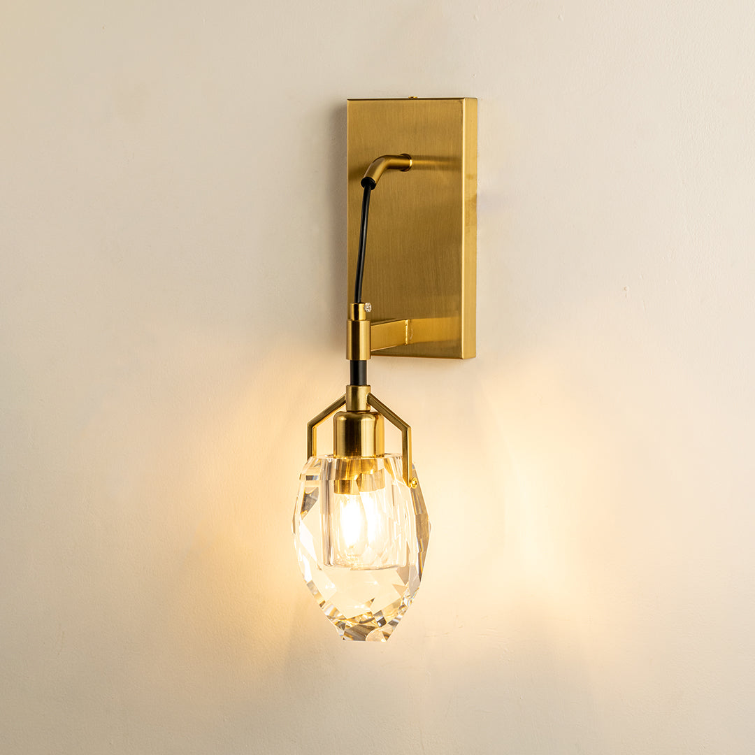 Gold metal wall light with clear glass shade emitting warm glow perfect for elegant interior wall decor styling.